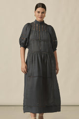 Woman wearing a dark gray dress with decorative elements on a beige background